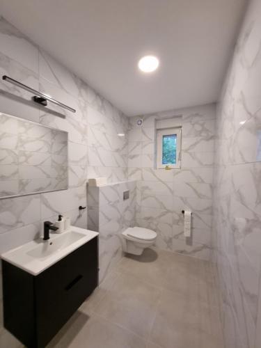 a white bathroom with a sink and a toilet at Ostoja in Ostrowo