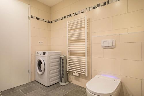 a bathroom with a washing machine and a toilet at Ferienwohnung Tannenblick in Höchst