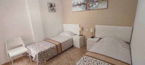 a bedroom with two beds and a chair at Apartamento EL MOLINO in Vecindario