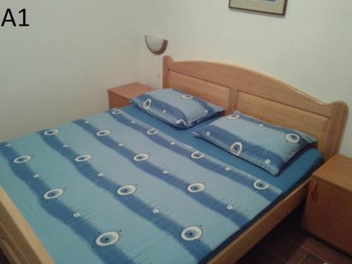 a bed with blue sheets and blue pillows on it at Apartments Belvedere - A1 in Nečujam