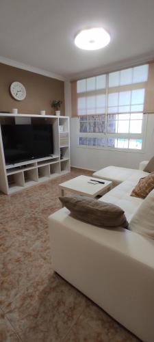 a living room with a white couch and a flat screen tv at Apartamento EL MOLINO in Vecindario