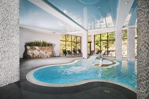 - une piscine avec une fontaine dans une pièce dotée de fenêtres dans l'établissement Hotel Żywiecki Medical SPA & Sport Żywiec, à Żywiec