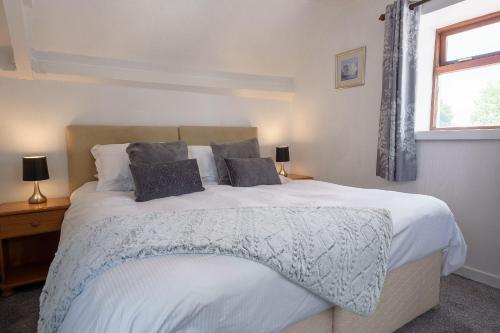 a bedroom with a large white bed with two pillows at Templand Cottage in Thornhill