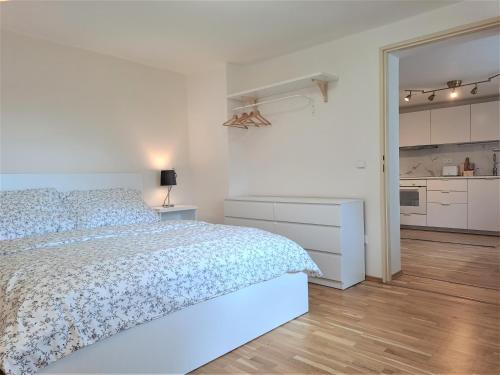 a white bedroom with a bed and a kitchen at Apartmánový dům se zahradou v klidné části Prahy in Prague