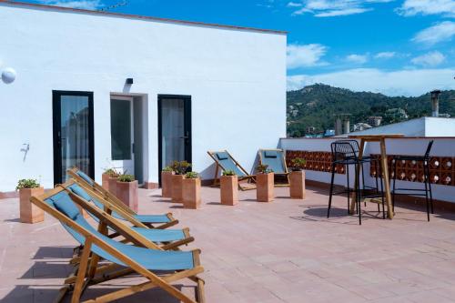 a patio with chairs and tables on a white building at Hostal Boutique Es Menut in Tossa de Mar