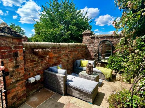 uma parede de tijolos com duas cadeiras de vime e um sofá em Tanyard Cottage - Whixley, York, North Yorkshire em York