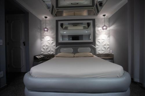 a bedroom with a white bed with lights on it at Hotel Show Adult Only in Rio de Janeiro