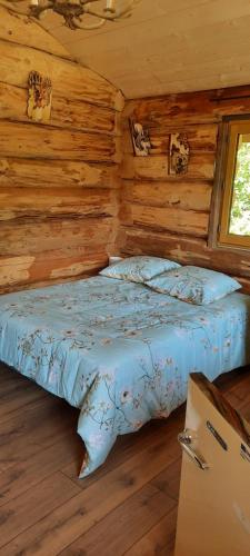 une chambre avec un lit dans une cabane en rondins dans l'établissement CHARLOTTE LA ROULOTTE, à Grosbreuil