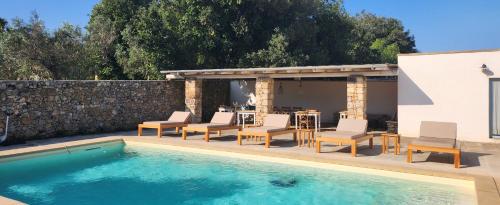 una piscina con sillas y una mesa junto a un edificio en Masseria Violante Boutique Hotel en Ruffano