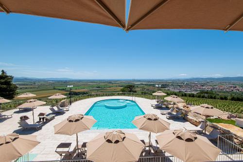a view of a swimming pool with umbrellas at Castello Bonaria Wine & Spa Resort in Campiglia Marittima