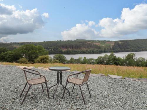 a table and two chairs sitting next to a lake at Llety Dewi in Oswestry