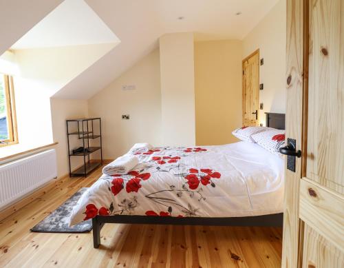 a bedroom with a bed with red flowers on it at Llety Dewi in Oswestry
