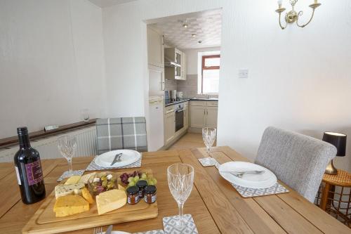 een houten tafel met een bord eten en een fles wijn bij Thomas Carlyle Cottage in Thornhill