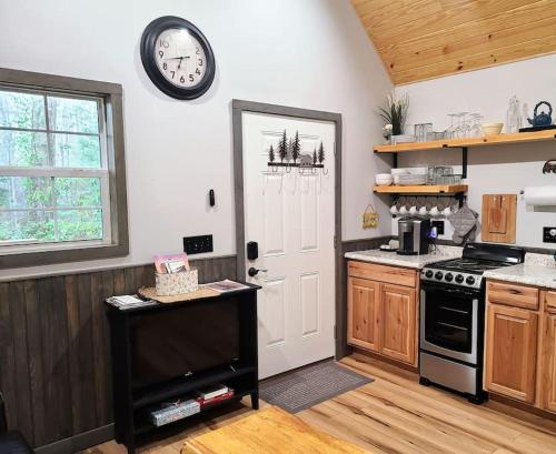 a kitchen with a stove and a clock on the wall at Holly Nest a Cozy Cabin Getaway near Gatlinburg in Cosby
