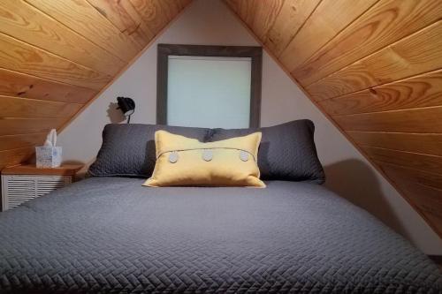 a bed with a yellow pillow on top of it at Holly Nest a Cozy Cabin Getaway near Gatlinburg in Cosby