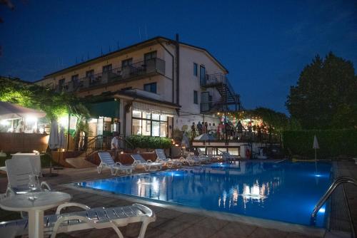 a swimming pool in front of a hotel at night at Hotel Stazione sul lago di Iseo in Paratico