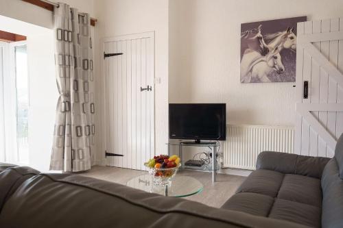 - un salon avec un canapé et une télévision dans l'établissement Jane Welsh Cottage, à Thornhill