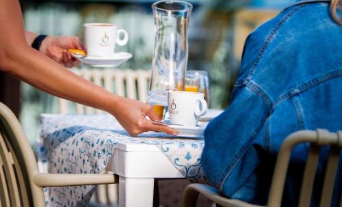 een persoon aan een tafel met twee kopjes koffie bij Hotel La Casona de Nueva in Nueva de Llanes