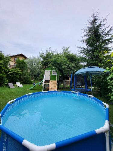 uma grande piscina azul com um parque infantil num quintal em Casa Bunicii Comarnic em Comarnic