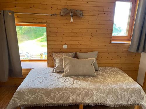 Ce lit se trouve dans une chambre en bois dotée d'une fenêtre. dans l'établissement Duplex « les 7 Marmottes », Les Balcons de Recoin, à Chamrousse