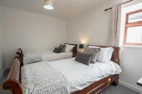 two beds in a small bedroom with a window at Drumlanrig Cottage in Thornhill