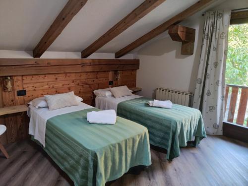 two beds in a room with wooden walls and wooden floors at A casa da Elide in Aymavilles