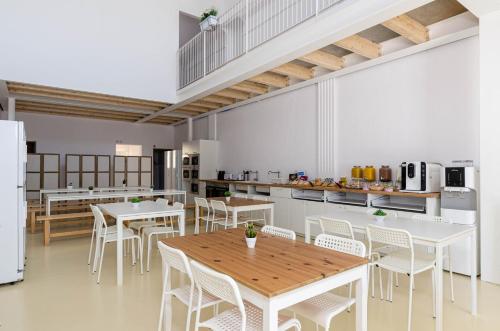a large kitchen with white tables and white chairs at Urban Hostel Palma - Albergue Juvenil - Youth Hostel in Palma de Mallorca