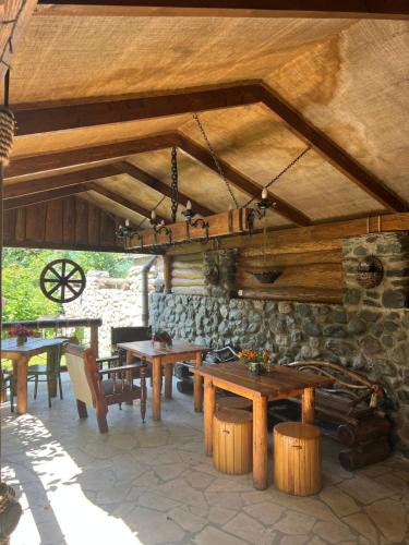 un patio con mesas de madera y una pared de piedra. en ARTSIV Guesthouse, en Dilijan