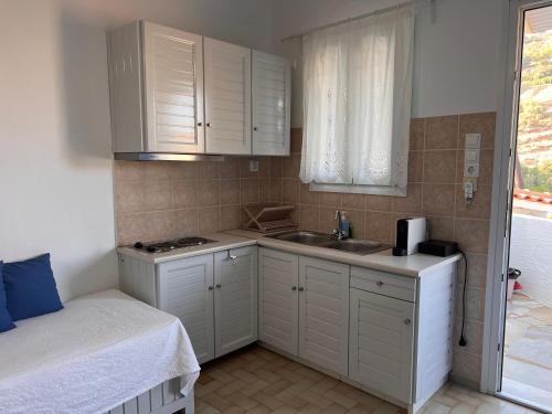 a small kitchen with white cabinets and a sink at Danaides Studios in Batsi