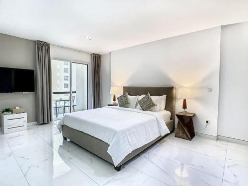 - une chambre blanche avec un grand lit et une télévision dans l'établissement Key View - Murjan 2, JBR, à Dubaï