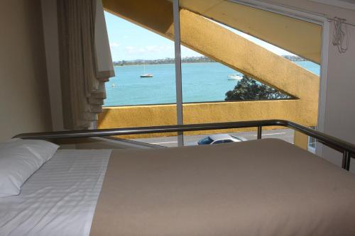 a bedroom with a bed and a view of the ocean at Bucklands Beach Waterfront Motel in Auckland