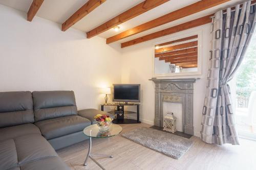 a living room with a couch and a fireplace at Dalgarnock Cottage in Thornhill