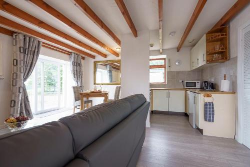a living room with a couch and a kitchen at Dalgarnock Cottage in Thornhill
