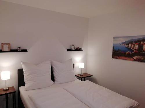 a bedroom with a white bed with two lamps at Premium Apartment mit Terrasse in Wörth