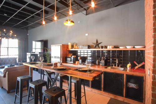 a kitchen with a large wooden table and stools at Brand New Gorgeous Industrial Loft in Downtown Ens in Ensenada