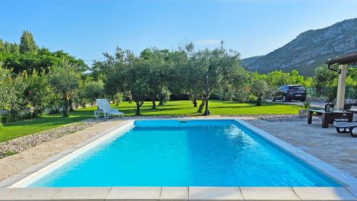 a swimming pool in a yard with a chair and trees at Holiday Home Natura with private pool in Mostar