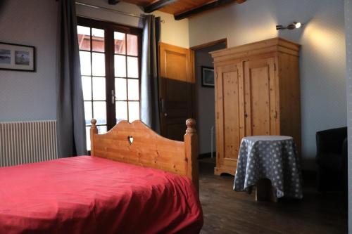 een slaapkamer met een rood bed en een houten kast bij La Grangerie in Aillon-le-Jeune