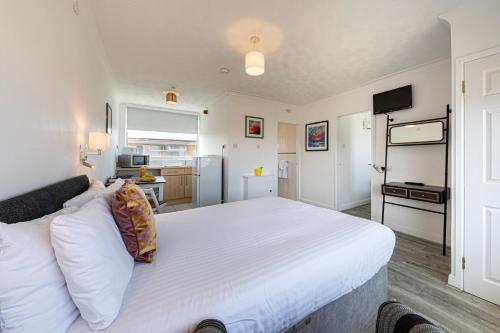 a bedroom with a large white bed and a kitchen at Beaches Chalets in Prestatyn
