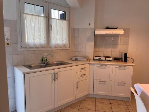 a kitchen with white cabinets and a sink and a window at Danaides Studios in Batsi