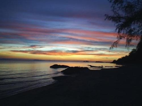 a sunset on a beach with a boat in the water at Bird Bungalow Koh Phangan in Haad Rin