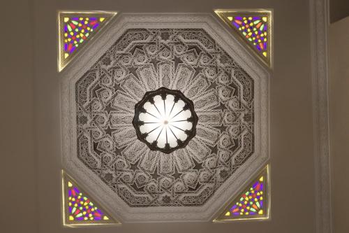 a room with a ceiling with a clock and stained glass at Riad Mandana & Spa in Marrakech