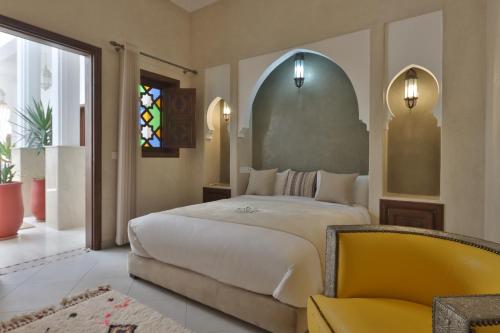 a bedroom with a large bed and a yellow chair at Riad Mandana & Spa in Marrakesh
