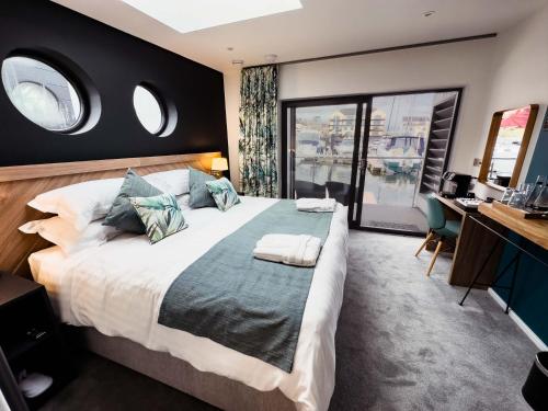 Rooms at The Deck, Penarth في كارديف: غرفة نوم بسرير كبير مع نافذتين