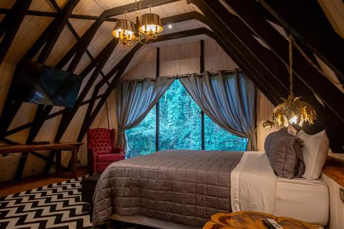 um quarto com uma cama e uma grande janela em Art BBQ Lodge em Campos do Jordão