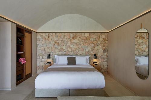 a bedroom with a large bed and a stone wall at Santorini Sky, The Retreat in Pyrgos