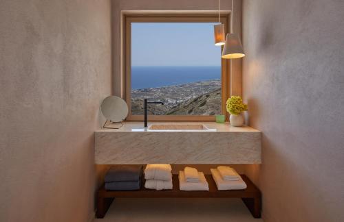 ein Bad mit einem Waschbecken und ein Fenster mit Handtüchern in der Unterkunft Santorini Sky, The Retreat in Pirgos