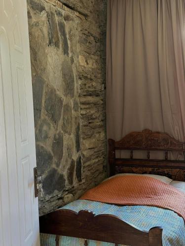 a bedroom with a stone wall and a bed at Guesthouse Divo Hut in Ushguli