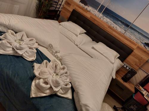 a bed with white sheets and two flowers on it at Happiness Apartman in Kecskemét