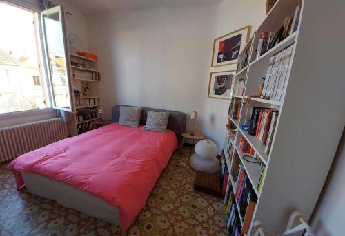 - une chambre avec un lit rouge et une étagère à livres dans l'établissement Hâvre de paix dans un écrin de verdure, à Avignon