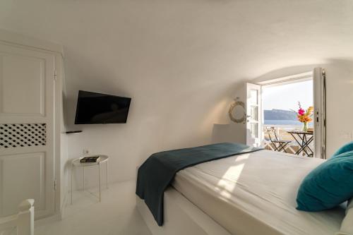 a white bedroom with a bed and a window at The Bay - Loft apartment Sea & Sunset View in Oia